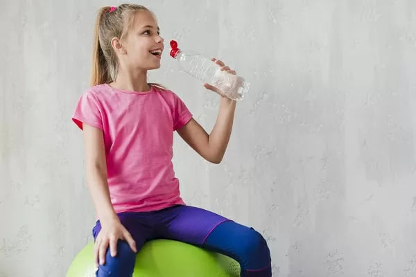 девочка на мяче пьёт воду